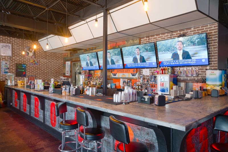 The bar at Cobo's — TVs overhead and a full lineup behind the counter
